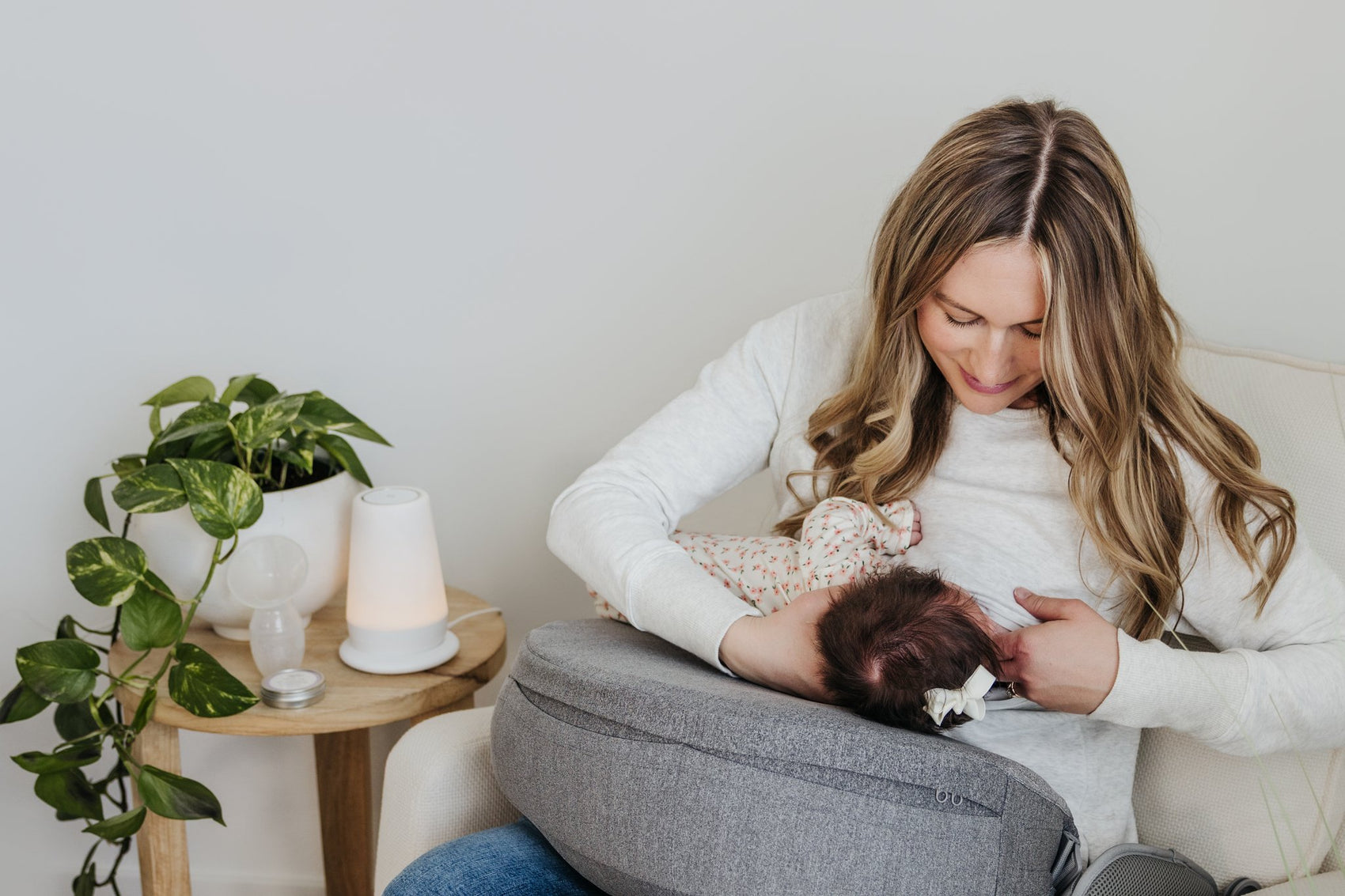 Woman holding a baby on a couch with a plant and candle in the background