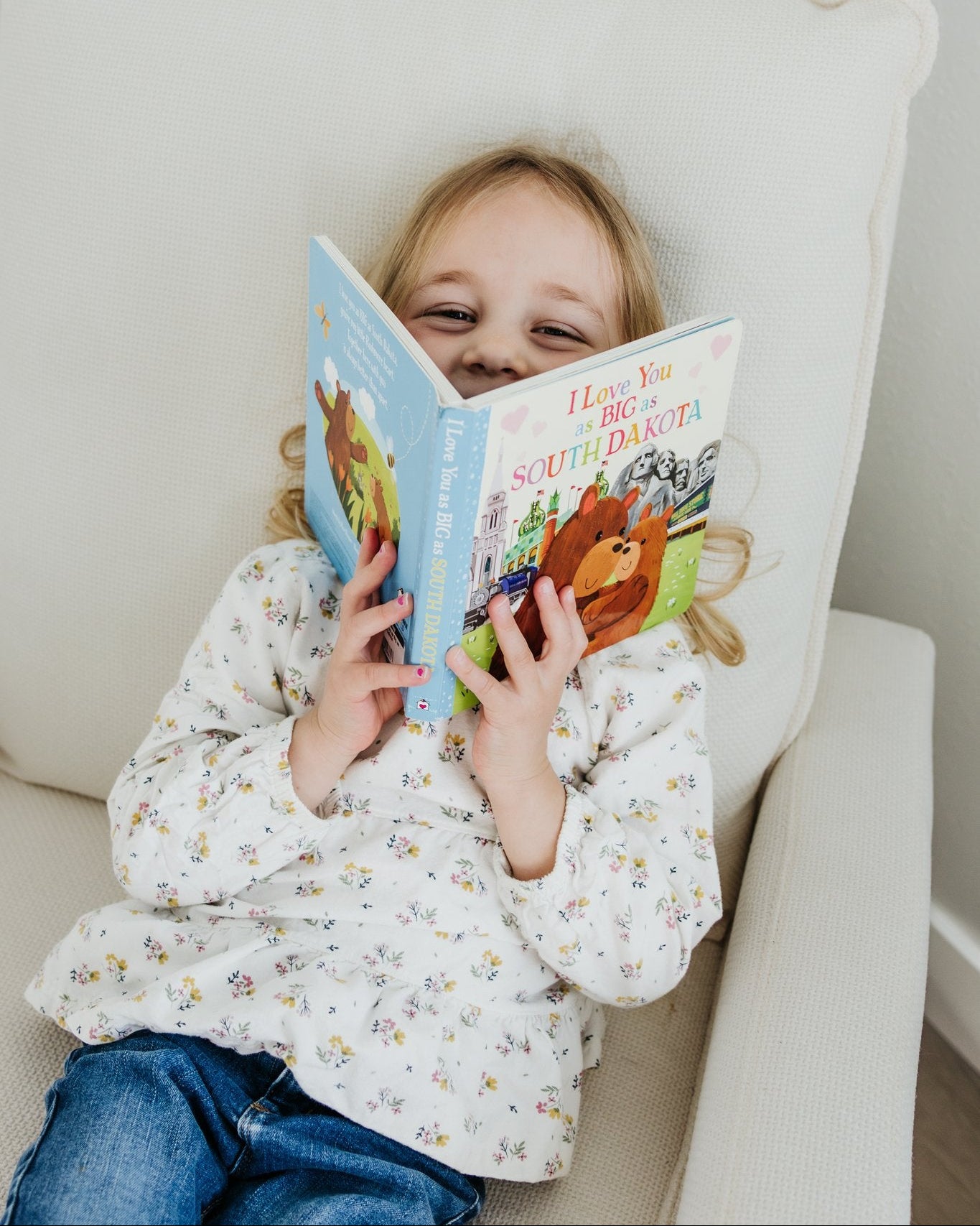 Child reading a book on a white chair